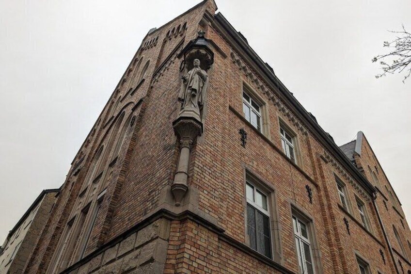 A corner of a brick building with a statue and a window. 5