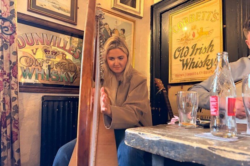 A person sitting at a table with a guitar, surrounded by framed signs and bottles. 2