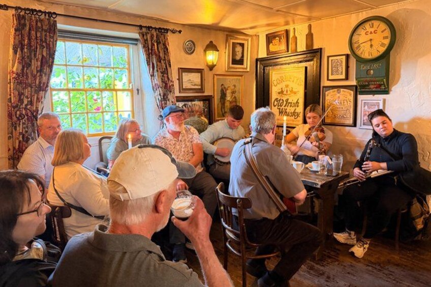 A group of people sitting at a table in a cozy, warmly lit room with a clock and framed pictures on the wall. 3