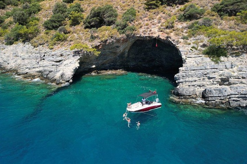 Ein Boot vor Anker in der Nähe einer felsigen Küste mit klarem, türkisblauem Wasser. 5