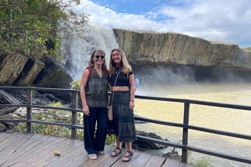 Two people standing on a wooden deck by a waterfall. 5