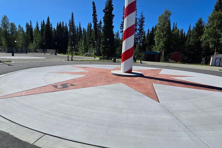 A roundabout with a red and white striped pole, surrounded by trees and a clear sky. 4
