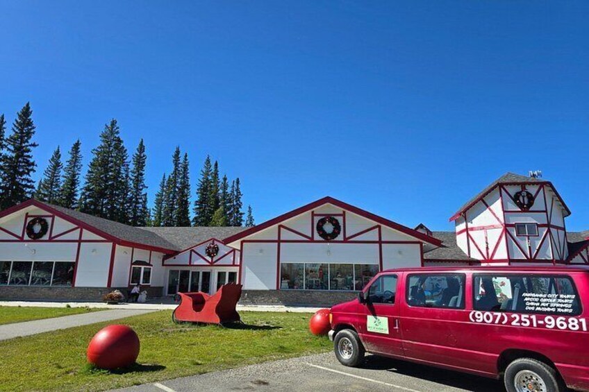 A red van parked in front of a building with a telephone number on its side. 2