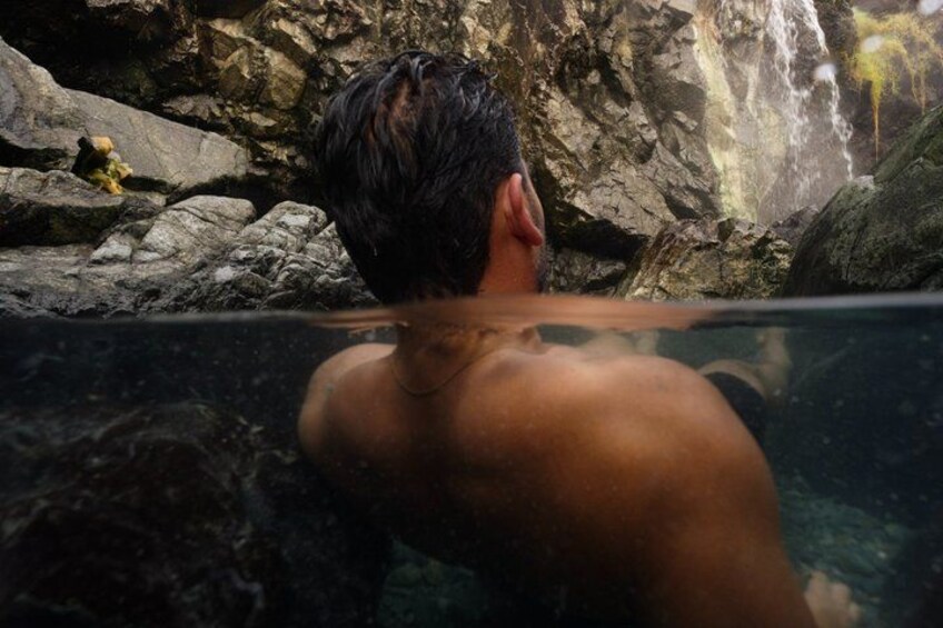 A person in a natural setting with a waterfall and rocky terrain. 3