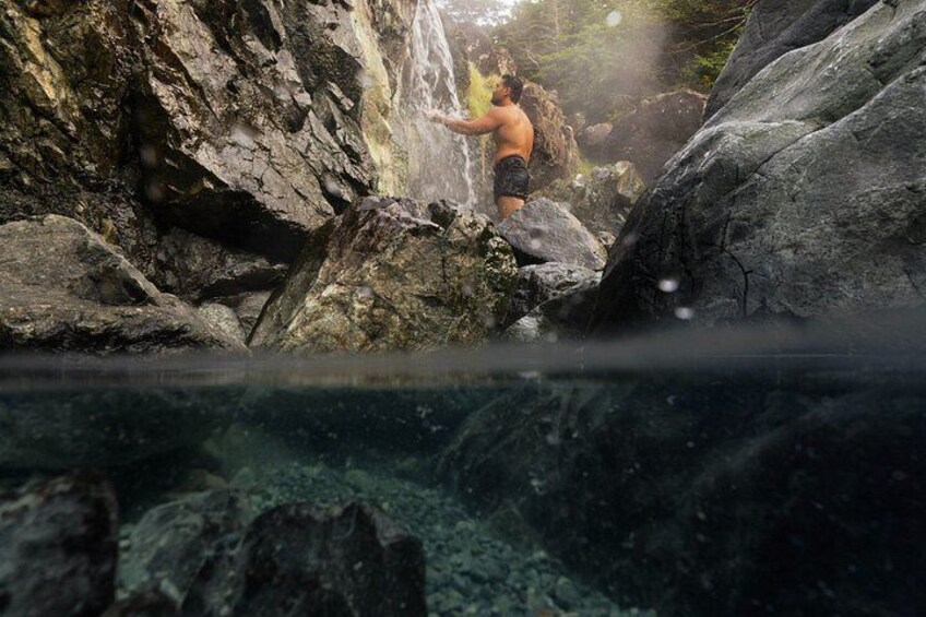 A person standing on rocks near a waterfall. 1