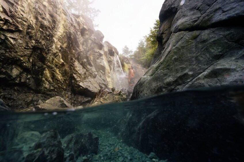 A rocky canyon with clear water and a person in the distance. 4