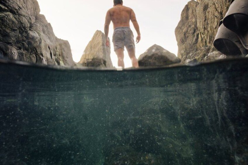 A man walking towards a rocky cliff edge. 3