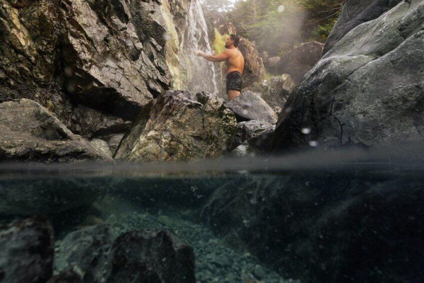 A person standing on rocks near a waterfall. 1