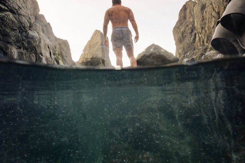 A person walking towards a rocky cliff edge. 3