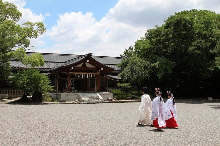 A traditional Japanese building with a tiled roof, surrounded by trees and a gravel courtyard. 2