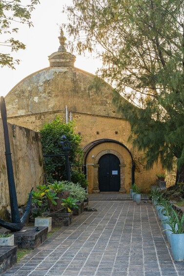 A historic building with a dome and arched entrance, surrounded by potted plants and a stone pathway. 2