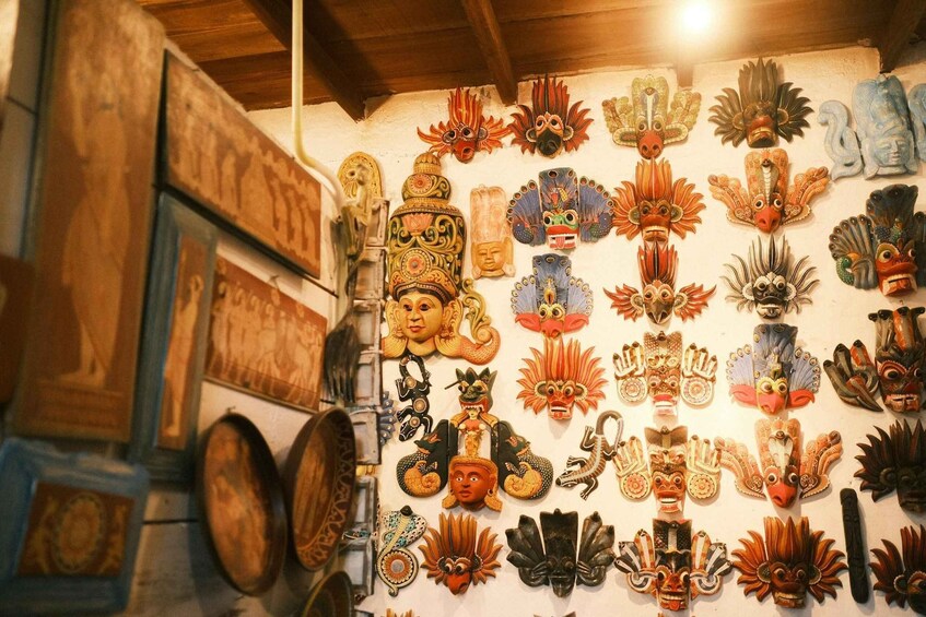 A variety of traditional masks and sculptures displayed on a wall. 4