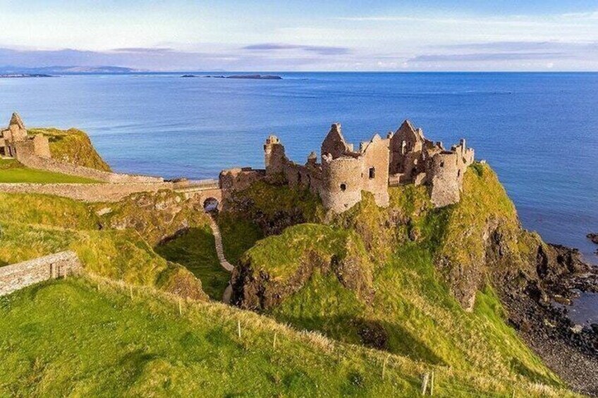 A historic castle on a grassy cliff overlooking the sea. 4