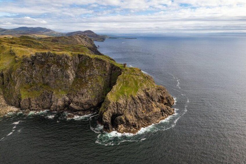A rugged coastline with cliffs and a small structure on top. 5