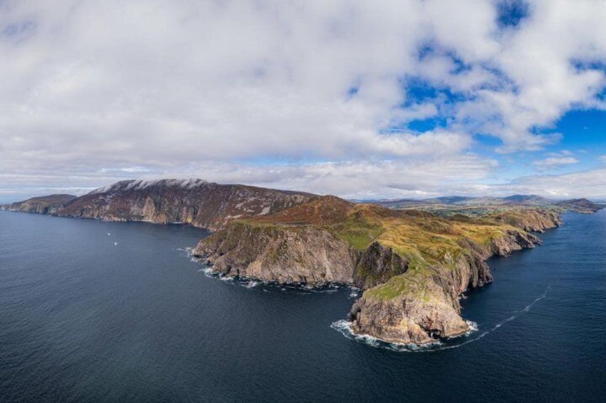 A rugged coastline with a small island surrounded by deep blue waters. 1