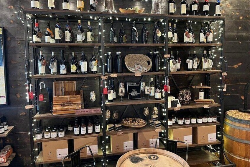 A wine cellar with shelves of bottles, wooden boxes, and barrels. 3