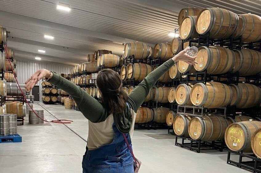A person in a winery, surrounded by rows of wooden barrels. 5