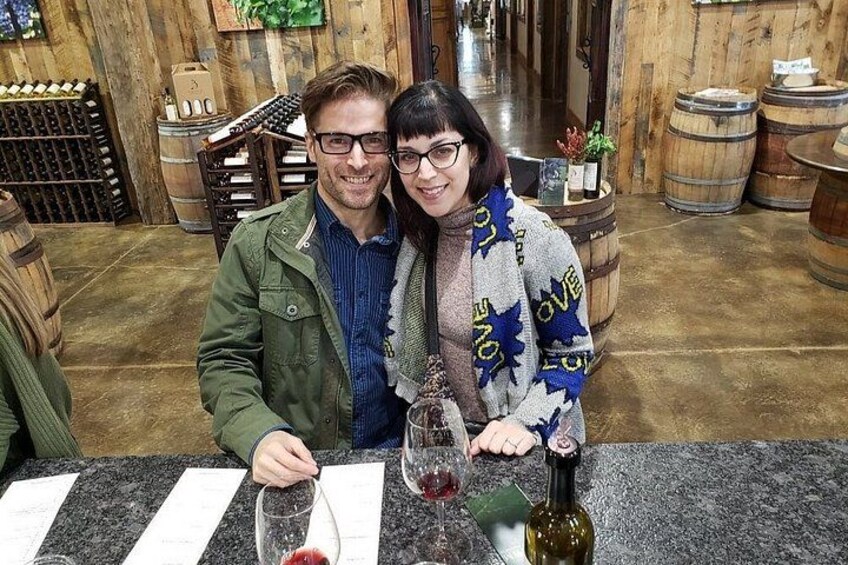 Two people at a bar with wine glasses and bottles. 2