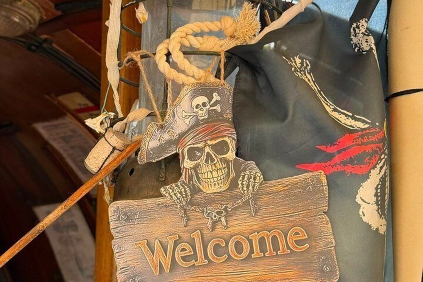 A wooden sign with a skull and crossbones, a rope, and a 'Welcome' sign. 3