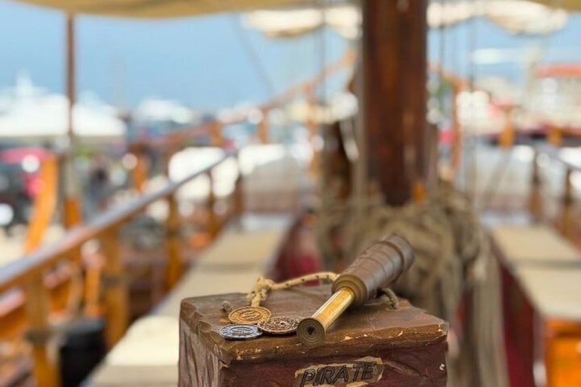 A wooden post with a brass telescope and coins on it, set against a blurred marina background with boats. 2