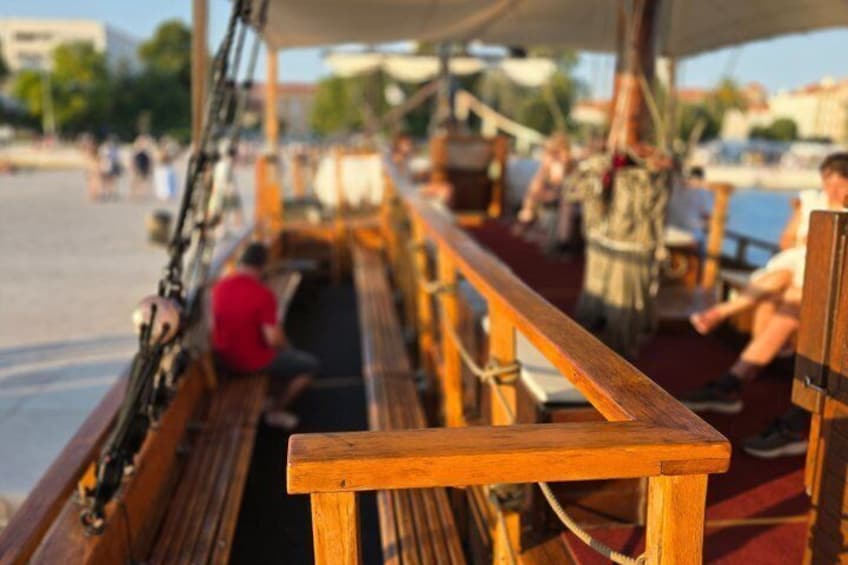 A wooden boat with benches, a person in a red shirt, and a body of water in the background. 5