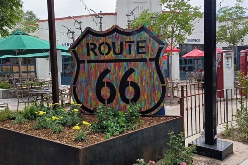 A colorful Route 66 sign surrounded by a planter with flowers. 4