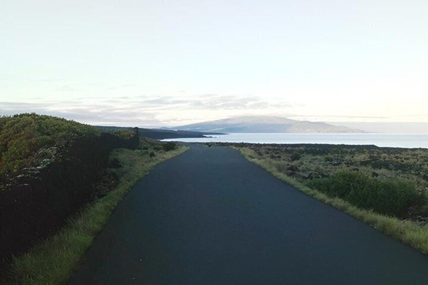 A narrow road flanked by grassy areas and a body of water. 5