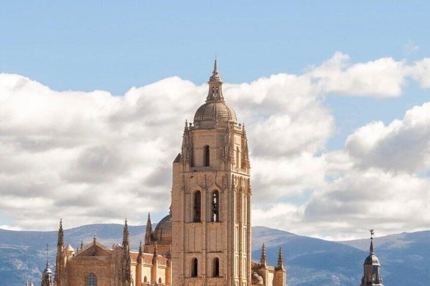 A large cathedral with a prominent dome and multiple spires, set against a backdrop of mountains and a partly cloudy sky. 4