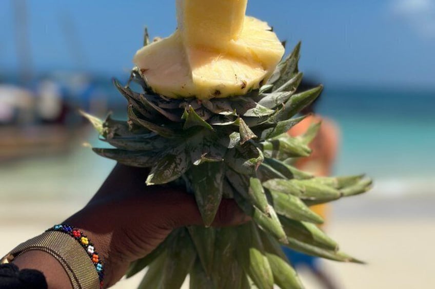 A hand holding a pineapple with a slice being removed. 4