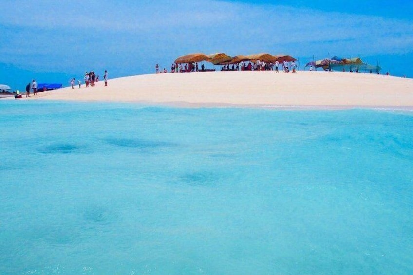 A beach with clear turquoise water, a sandy shore, and several thatched-roof structures. 3