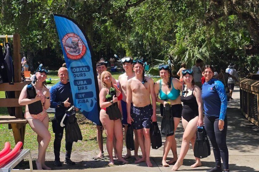 A group of people at a beach with a flag indicating a diving event. 1