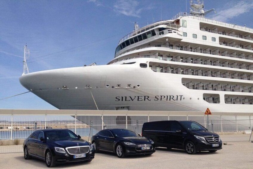 A large cruise ship named 'SILVER SPIRIT' docked at a port with three cars parked in front. 5