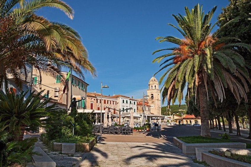 A town square with palm trees, a fountain, and historic buildings. 3