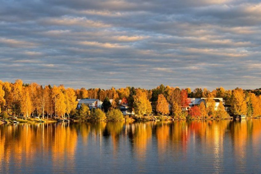 A lake with autumn-colored trees reflecting on the water, surrounded by houses. 2