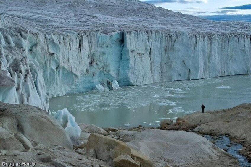 A glacier with a person standing at the edge. 1