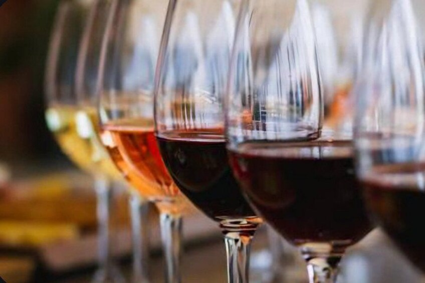 A row of wine glasses filled with different colored liquids. 4