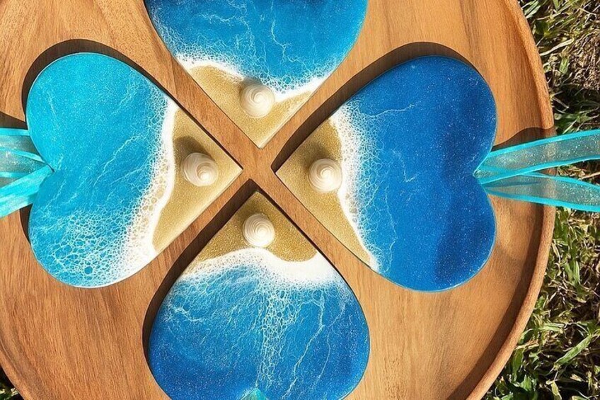 A wooden tray with four blue glass pieces, each with a wave pattern, and a small white object in the center. 1