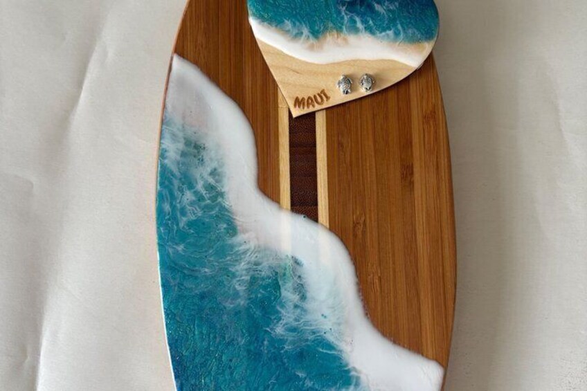 A wooden surfboard with a blue and white design, featuring the word 'MAUI' on it. 2
