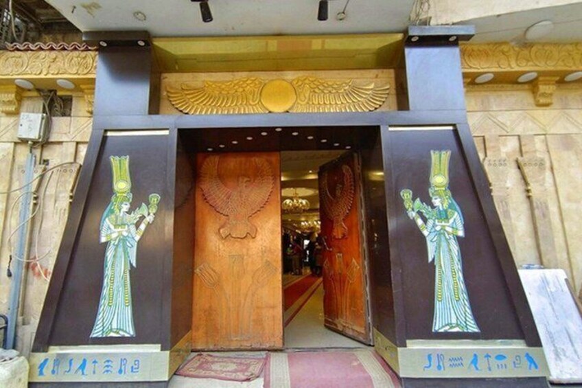 A building entrance with Egyptian-style carvings and a large wooden door. 1