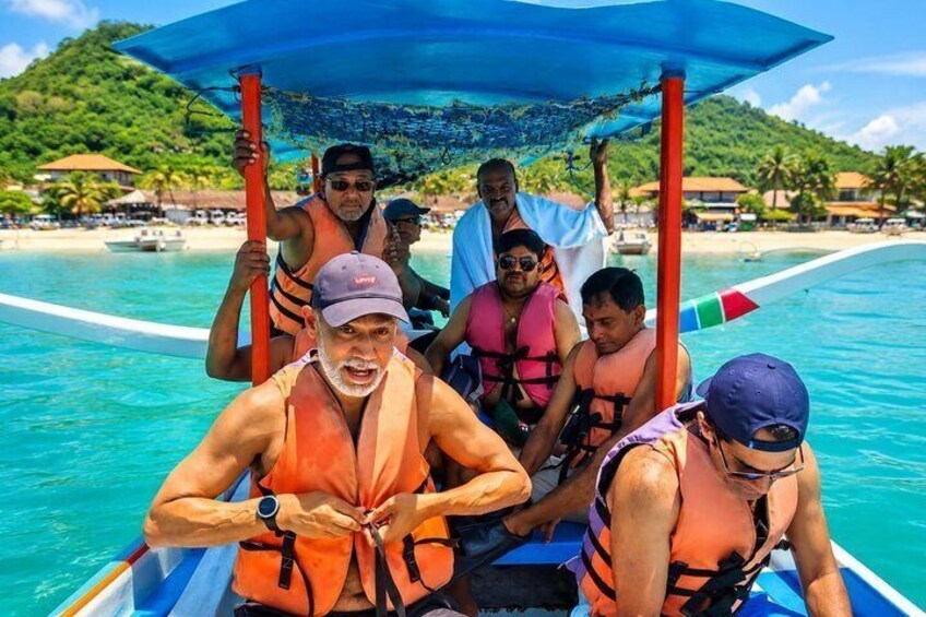 A group of people on a boat with an umbrella, wearing life jackets, and a tropical beach in the background. 3