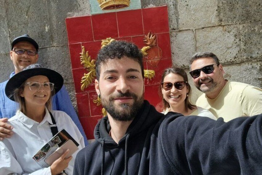 A group of people taking a selfie in front of a red and gold decorative wall. 4