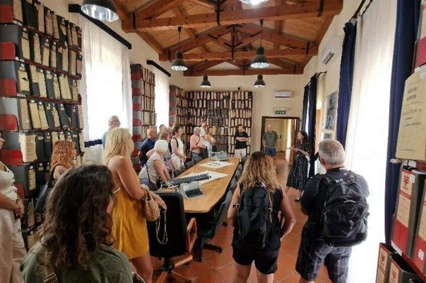A group of people in a room with bookshelves and a long table, possibly a library or bookstore. 5