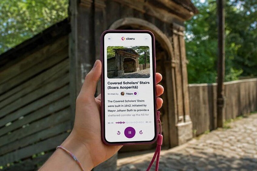 A hand holding a smartphone displaying a historical building with a covered staircase. 1