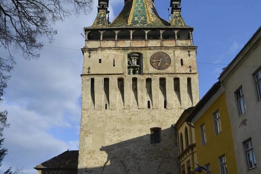 A historic tower with a clock, a green roof, and a weathered facade. 3