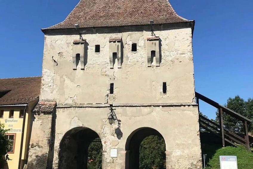 A historic building with a tower, arched entrance, and a sign. 2