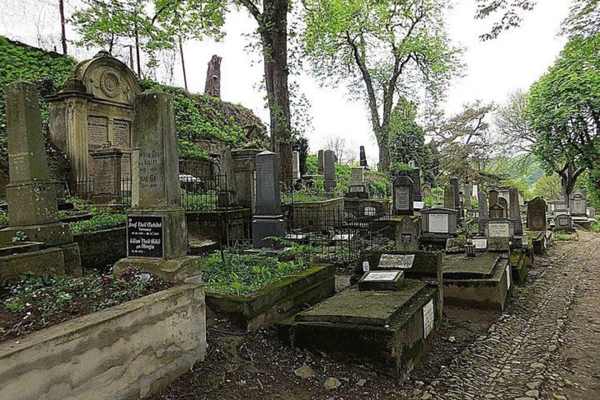 A cemetery with various headstones and tombstones, surrounded by trees and greenery. 5
