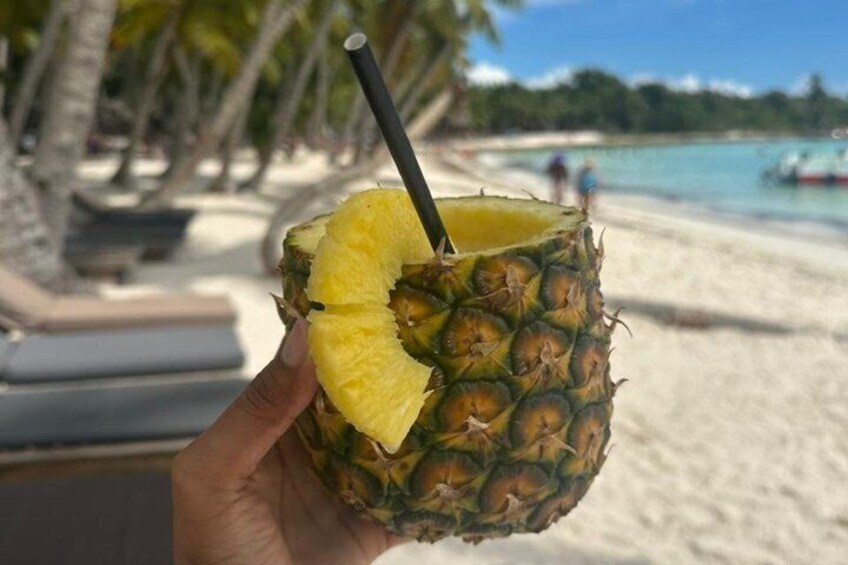 A hand holding a pineapple with a straw. 2
