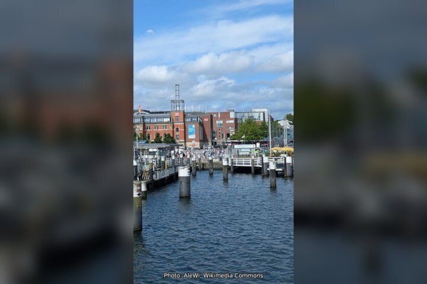 A waterfront with a red brick building, a dock, and a clear sky. 3