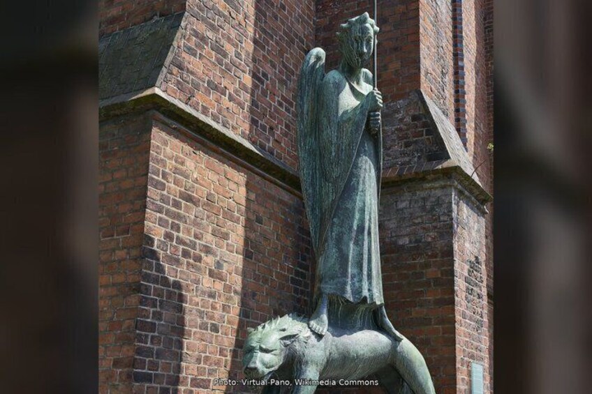 A statue of an angel with a lion, set against a brick building. 4