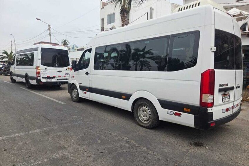 A white van parked on a street with buildings and palm trees in the background. 3